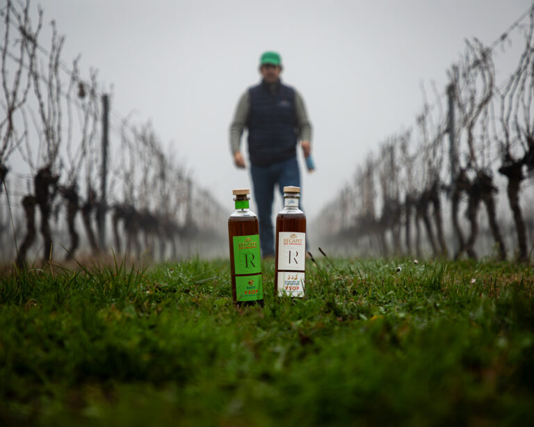 Deux bouteilles d’Armagnac Récapet au premier plan, avec une silhouette floue en arrière-plan